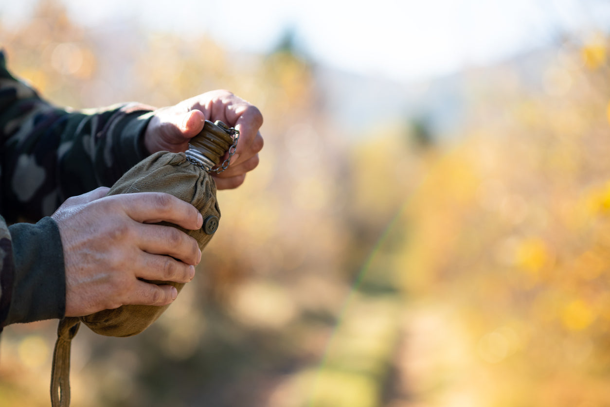 man holding an aluminium canteen of water