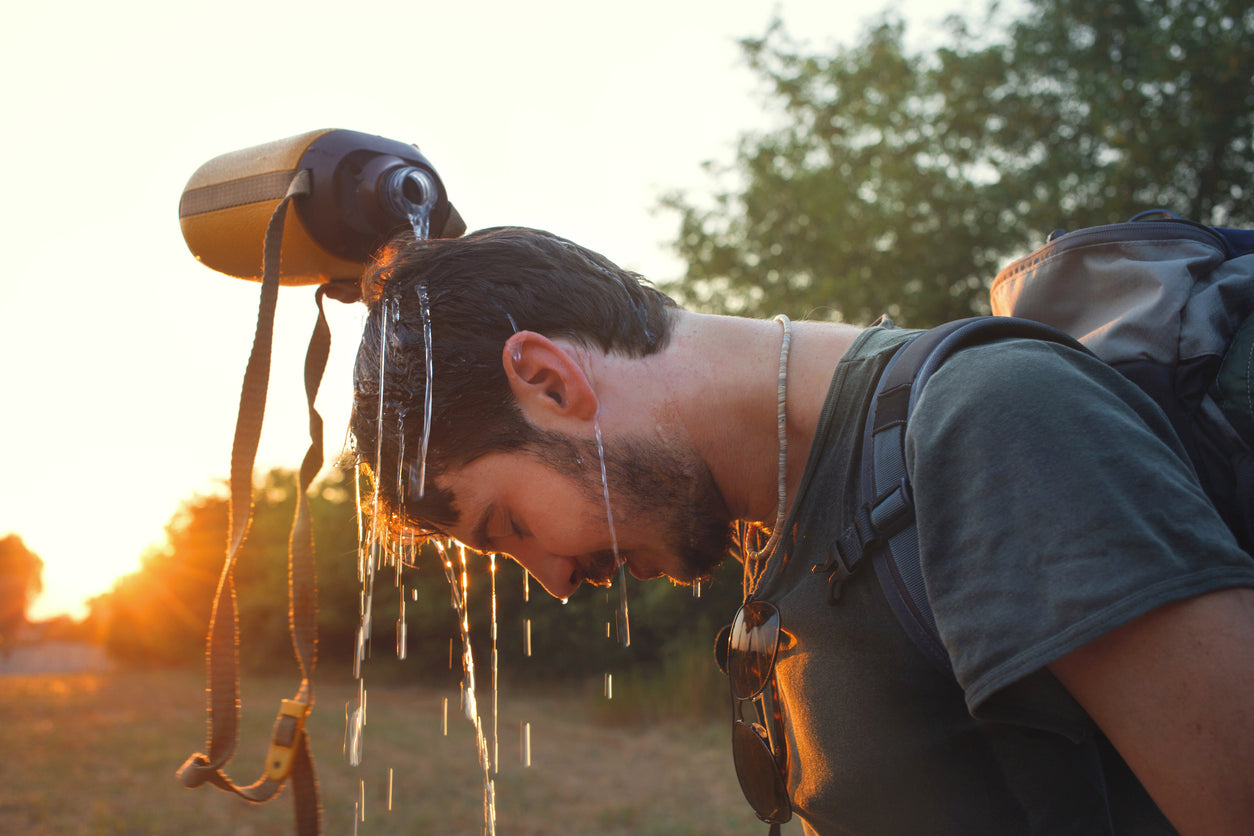 a hiker pouring water over his head in the heat